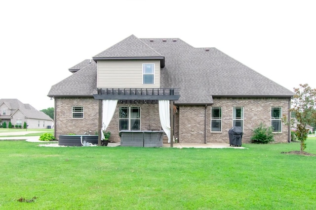 back of house featuring a pergola, a patio area, a yard, and brick siding