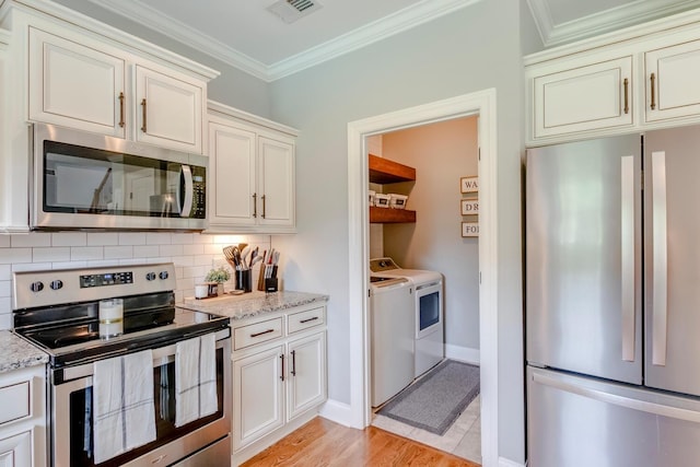 kitchen with independent washer and dryer, visible vents, backsplash, light stone countertops, and appliances with stainless steel finishes