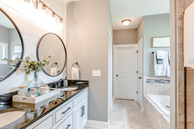 full bath featuring a relaxing tiled tub, tile patterned floors, double vanity, and a sink