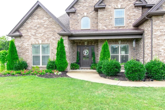 doorway to property featuring a yard and brick siding