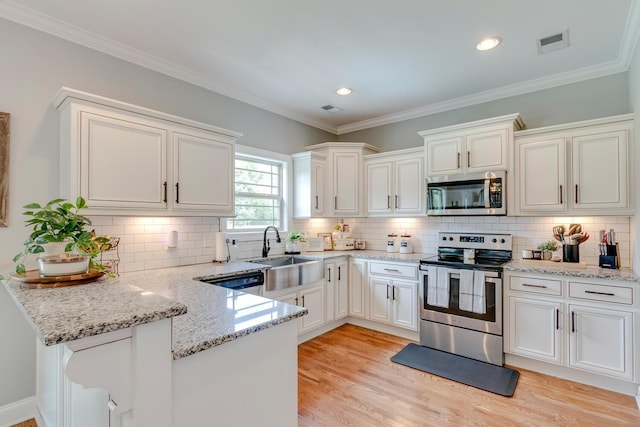 kitchen featuring visible vents, a sink, white cabinetry, a peninsula, and stainless steel appliances