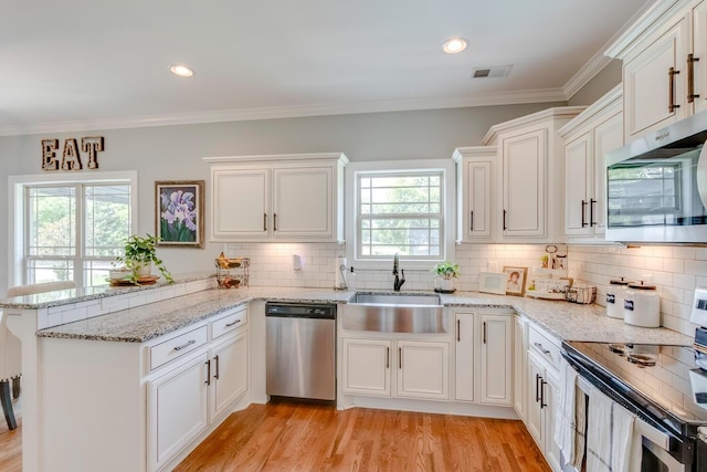 kitchen featuring a sink, a peninsula, stainless steel appliances, visible vents, and white cabinetry
