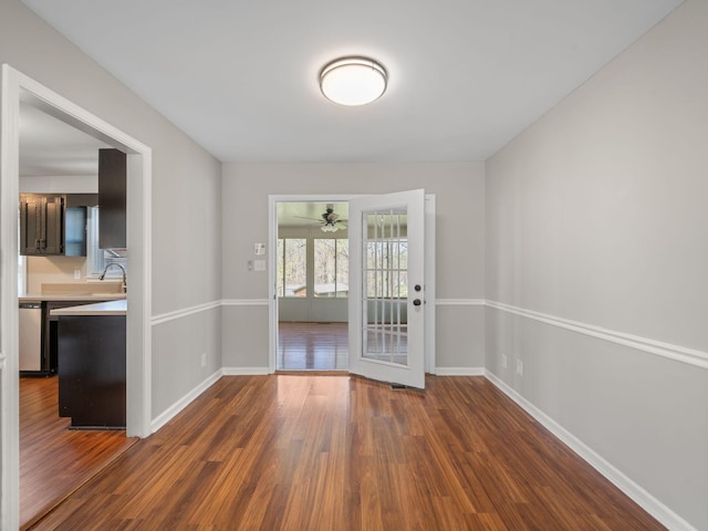 unfurnished room with baseboards, dark wood finished floors, and ceiling fan