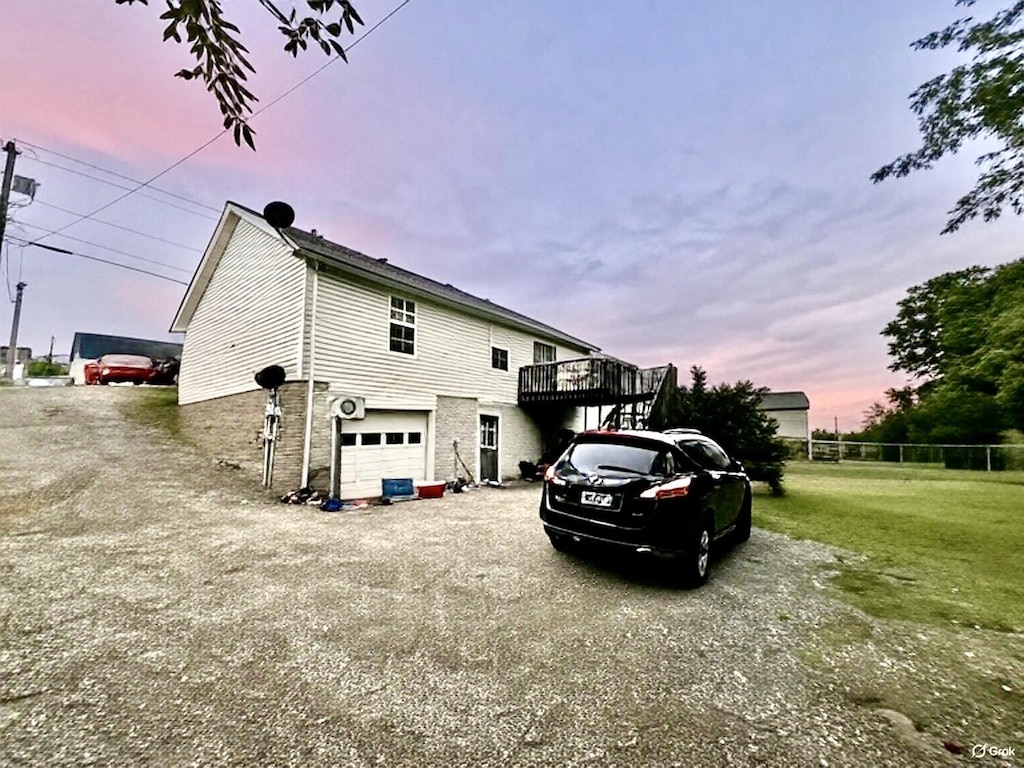 property exterior at dusk featuring driveway, a garage, and a deck