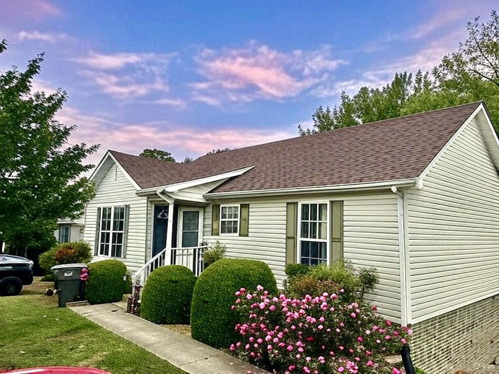 single story home featuring a front lawn and roof with shingles