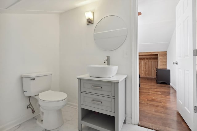bathroom featuring toilet, baseboards, vanity, and wood finished floors