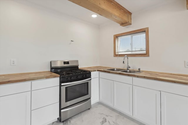 kitchen featuring a sink, stainless steel gas stove, white cabinetry, marble finish floor, and butcher block counters