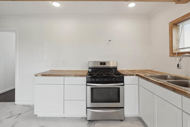 kitchen with a sink, wood counters, marble finish floor, gas stove, and ornamental molding