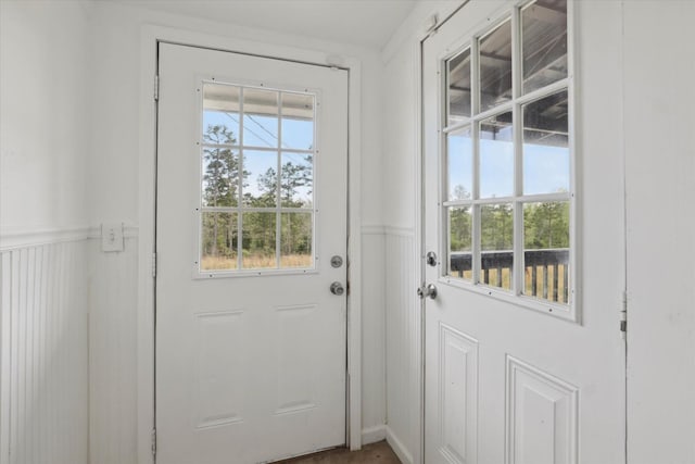 doorway to outside with a wainscoted wall