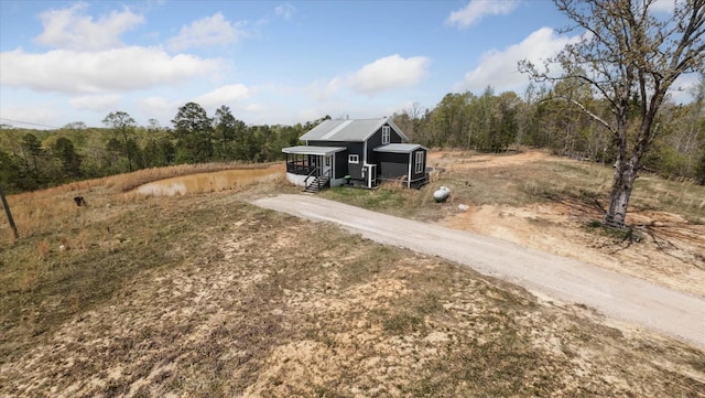 exterior space featuring a forest view and aphalt driveway