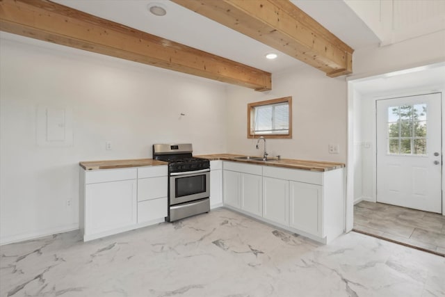 kitchen featuring gas range, butcher block counters, white cabinets, and marble finish floor