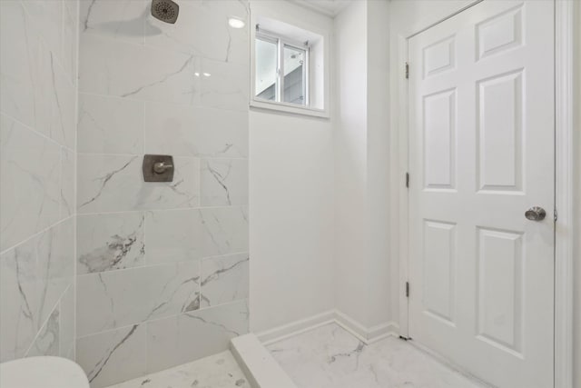 bathroom with toilet, baseboards, marble finish floor, and a tile shower