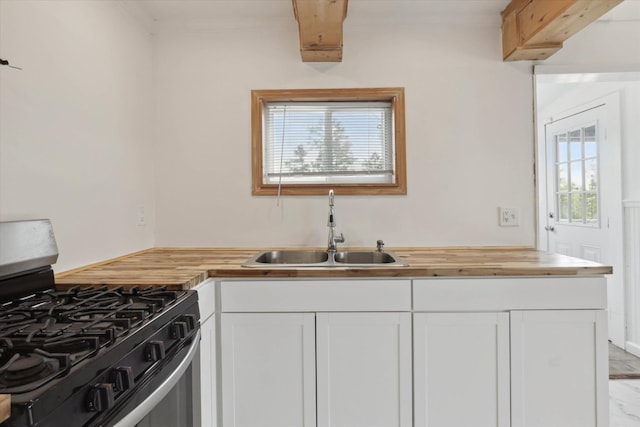 kitchen featuring butcher block countertops, a sink, crown molding, stainless steel range with gas stovetop, and white cabinets