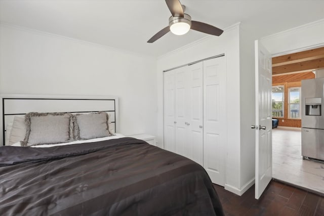 bedroom featuring a ceiling fan, a closet, crown molding, stainless steel refrigerator with ice dispenser, and dark wood-type flooring