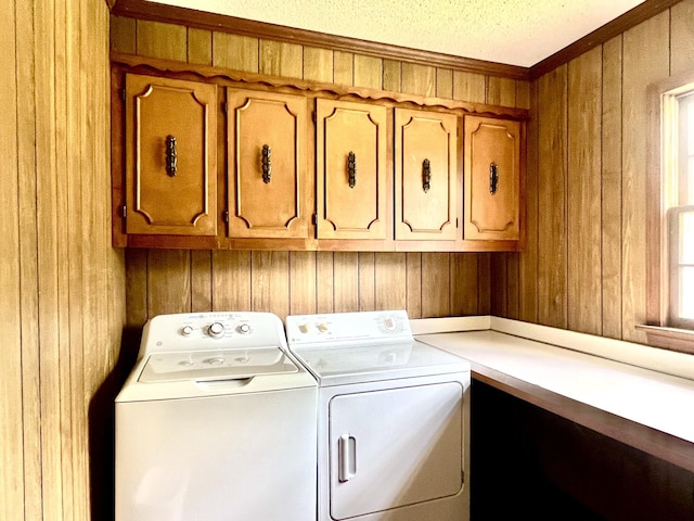 washroom with wood walls, washer and dryer, crown molding, and cabinet space