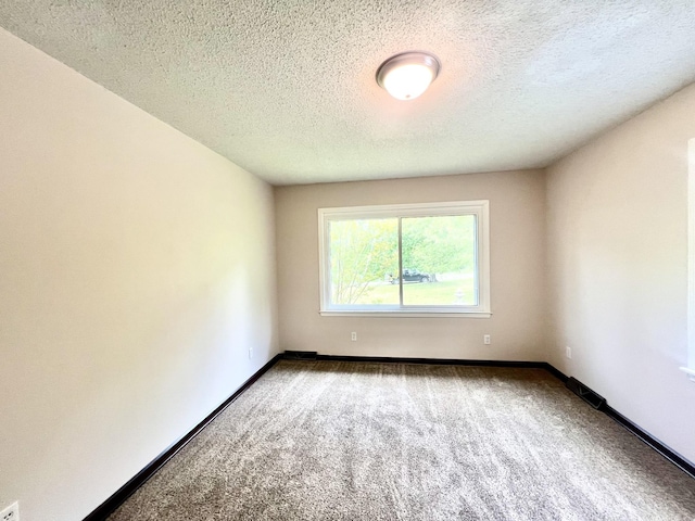 carpeted empty room with a textured ceiling and baseboards