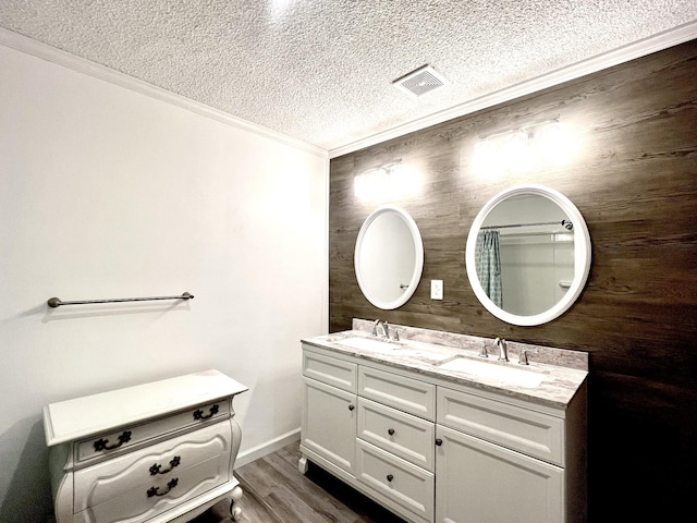 bathroom with a textured ceiling, double vanity, a sink, and wood finished floors