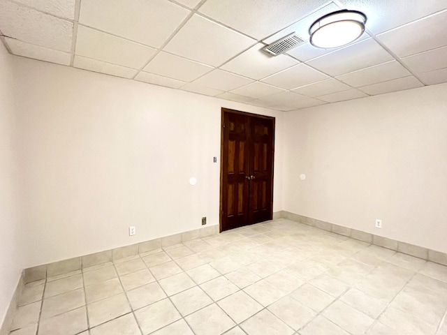 empty room featuring a paneled ceiling, light tile patterned floors, and visible vents