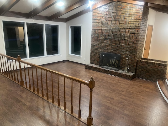 unfurnished living room with wood finished floors, a brick fireplace, and vaulted ceiling with beams