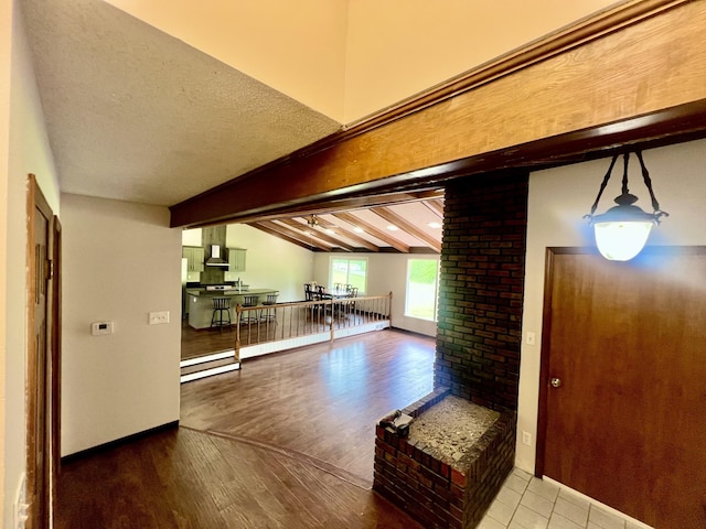 entrance foyer featuring baseboards, vaulted ceiling with beams, and wood finished floors
