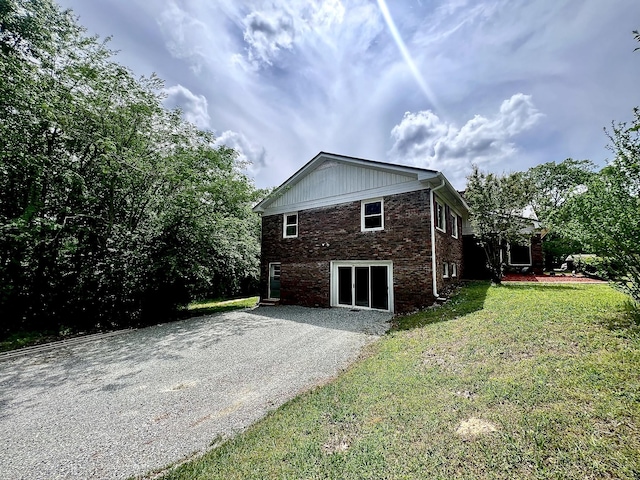 view of property exterior with a yard, driveway, and brick siding