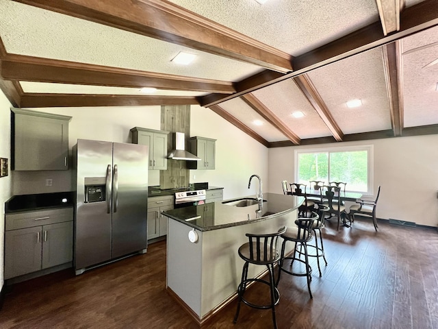 kitchen with a sink, dark countertops, wall chimney exhaust hood, stainless steel appliances, and a textured ceiling