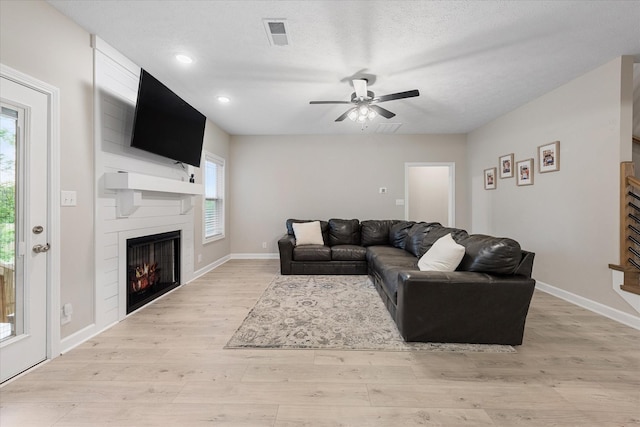 living room with light wood-style floors, a fireplace, baseboards, ceiling fan, and recessed lighting