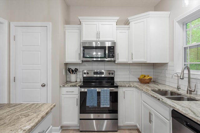 kitchen featuring stainless steel appliances, a sink, and white cabinetry