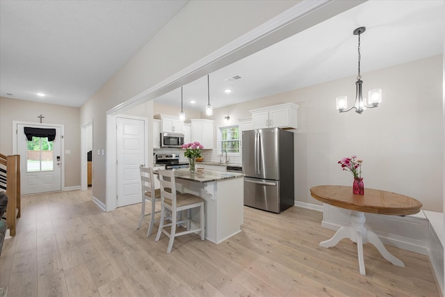 kitchen with stainless steel appliances, a kitchen island, white cabinets, light wood-style floors, and recessed lighting