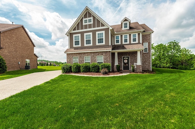 craftsman-style house with central AC unit, a shingled roof, a front lawn, and brick siding