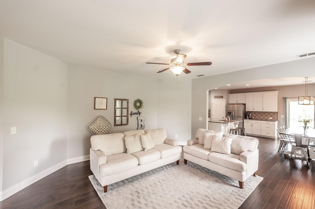 living area with ceiling fan, visible vents, baseboards, and dark wood-type flooring