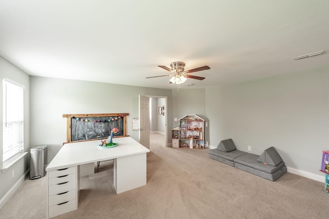 home office featuring baseboards, ceiling fan, visible vents, and light colored carpet