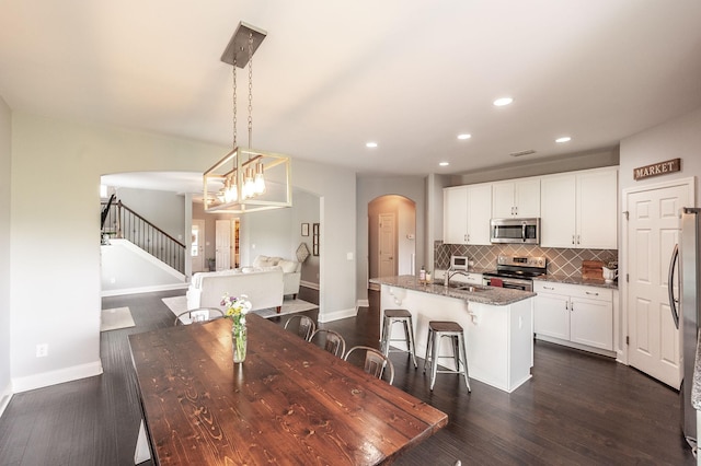 dining area with recessed lighting, baseboards, stairs, arched walkways, and dark wood-style floors