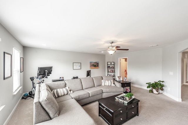 carpeted living area with baseboards, a ceiling fan, and arched walkways