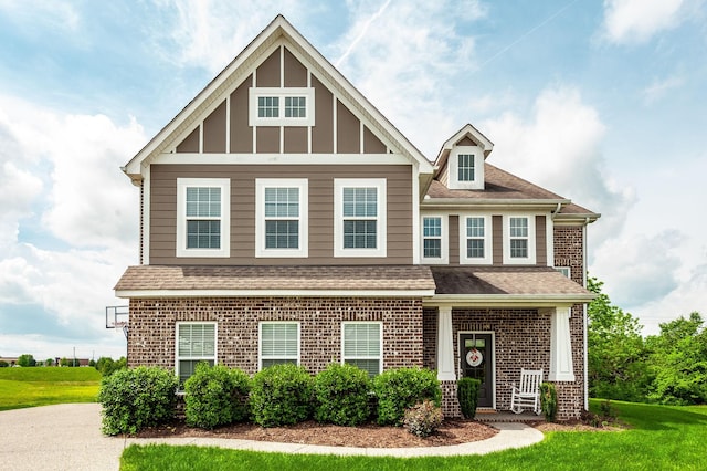 craftsman house featuring a front lawn, brick siding, and a shingled roof