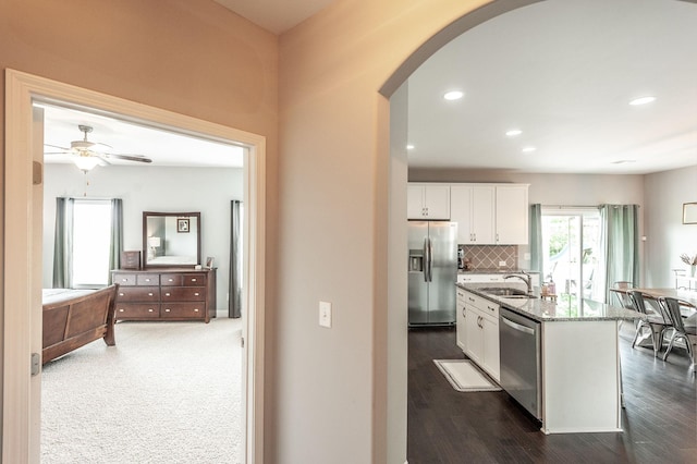 kitchen with white cabinets, stainless steel appliances, arched walkways, and a sink