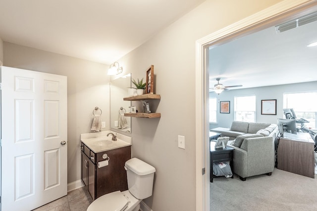 bathroom featuring toilet, vanity, visible vents, ceiling fan, and baseboards