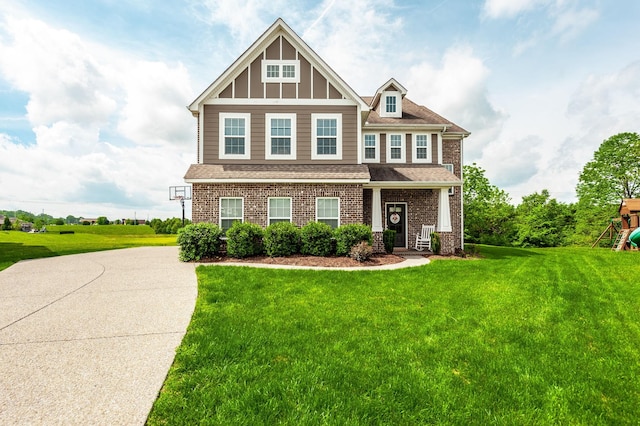 craftsman inspired home with a playground, brick siding, roof with shingles, and a front yard