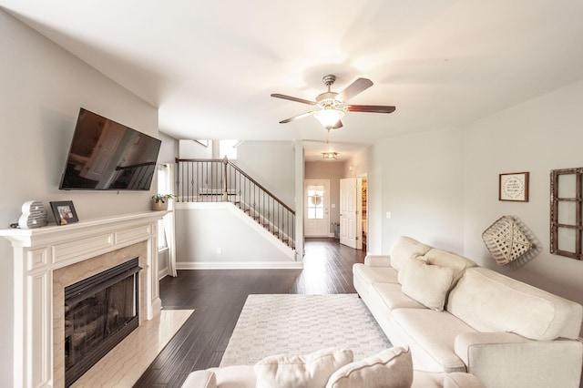 living room with baseboards, ceiling fan, stairs, dark wood-type flooring, and a fireplace