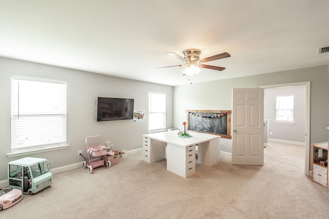interior space featuring light colored carpet, baseboards, and ceiling fan