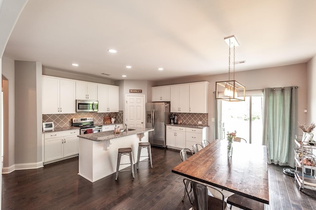 kitchen featuring recessed lighting, an island with sink, white cabinetry, decorative backsplash, and appliances with stainless steel finishes