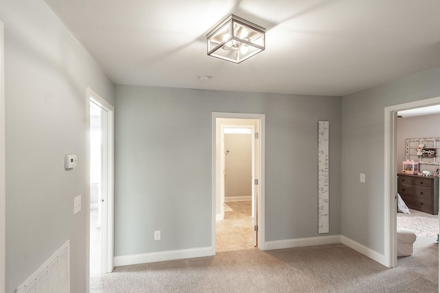 unfurnished bedroom with baseboards, light carpet, and visible vents