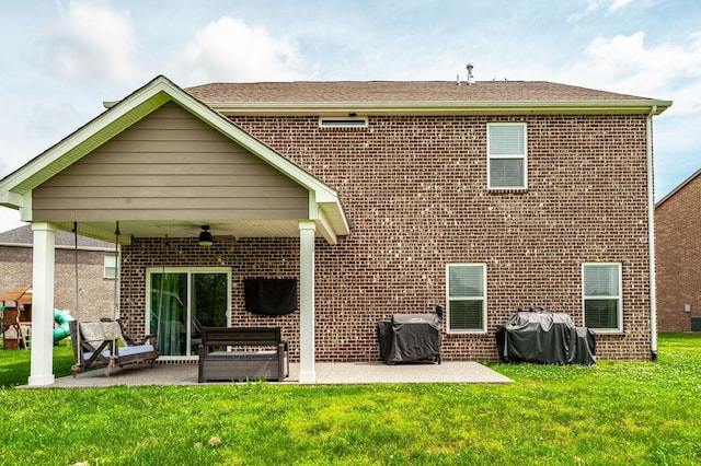 rear view of house featuring a ceiling fan, a yard, a patio, and brick siding