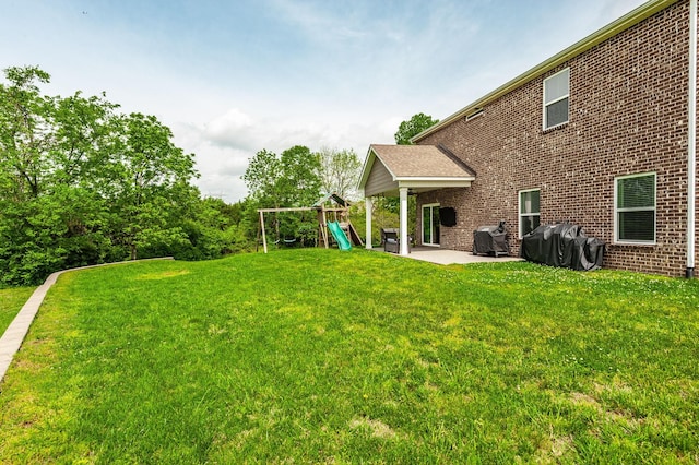 rear view of house with a yard, a playground, a patio, and brick siding