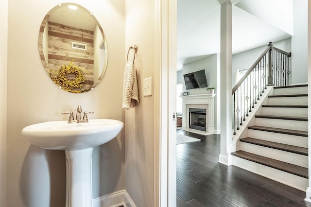 bathroom featuring baseboards, a fireplace with flush hearth, visible vents, and wood finished floors