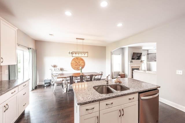 kitchen with a sink, dark wood-type flooring, baseboards, arched walkways, and dishwasher