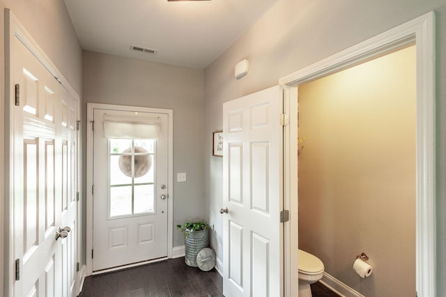 doorway to outside with baseboards, visible vents, and dark wood-type flooring