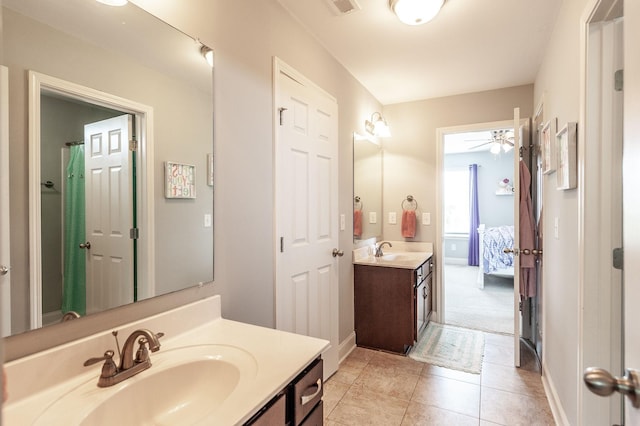 ensuite bathroom with a sink, tile patterned flooring, two vanities, and baseboards