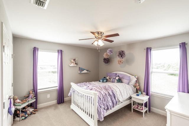 bedroom featuring multiple windows, light carpet, baseboards, and visible vents