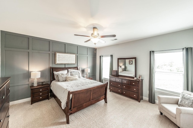 bedroom with a ceiling fan, light carpet, visible vents, and baseboards